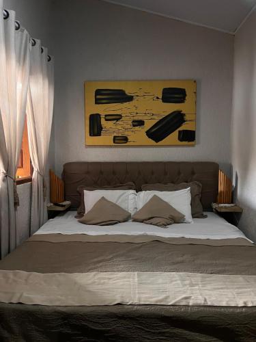 a bed in a bedroom with a painting above it at Villas House in Pirenópolis