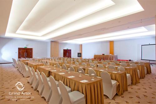 a large banquet hall with long tables and white chairs at Grand Artos Hotel & Convention in Magelang