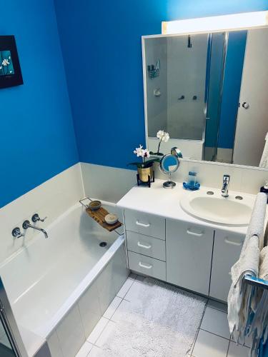 a bathroom with a white tub and a sink at Charming Townhouse Kirra Beach in Tweed Heads
