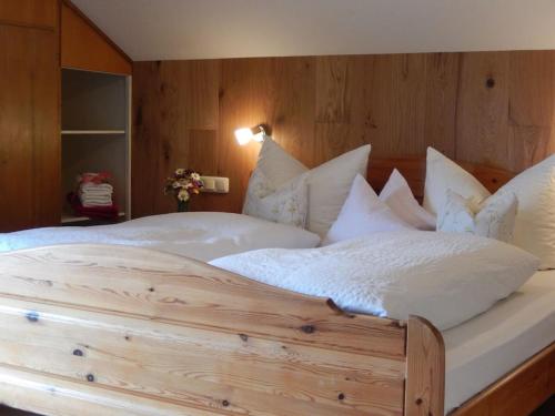 een groot houten bed met witte lakens en kussens bij III in the Anton house in Obermaiselstein