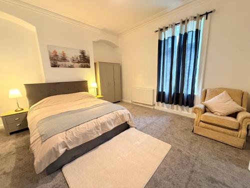 a bedroom with a bed and a chair and a window at Cosy Bungalow house in the centre of Sunderland in Sunderland