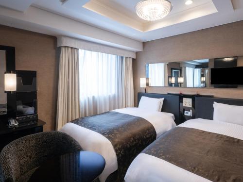 a hotel room with two beds and a television at APA Hotel Higashi Shinjuku Kabukicho in Tokyo