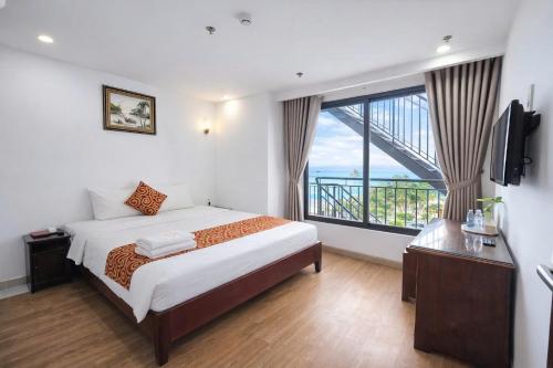 a bedroom with a bed and a large window at LE SOLEIL HOTEL managed by NEST Group in Nha Trang