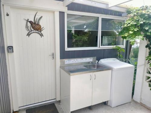 una cucina con lavello e lavatrice di Self-Contained Sleep out a Motueka