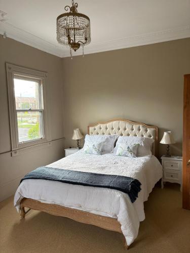 een slaapkamer met een groot bed met een kroonluchter bij Rosewood Terrace in Bathurst