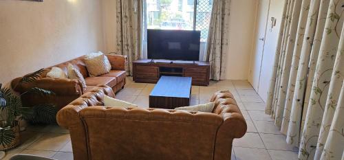 a living room with couches and a flat screen tv at Heart of Townsville tranquillity in Ross River