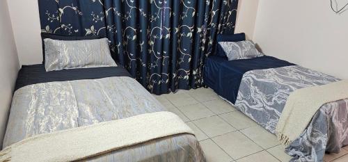 two twin beds in a room with blue curtains at Heart of Townsville tranquillity in Ross River
