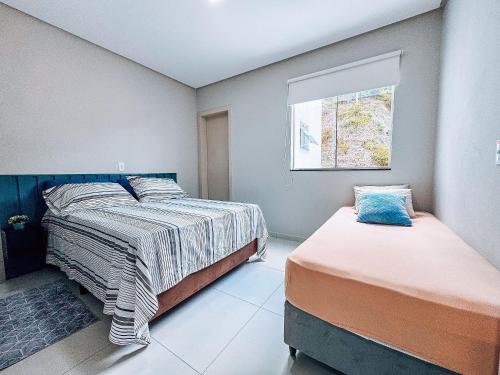 ein Schlafzimmer mit zwei Betten und einem Fenster in der Unterkunft Casa Nova e Completa | 2 Suítes com Ar | Área Gourmet | 2 Vagas in Brusque