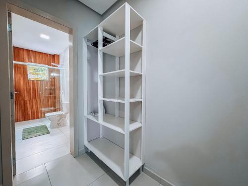 ein Badezimmer mit einem weißen Bücherregal in einem Zimmer in der Unterkunft Casa Nova e Completa | 2 Suítes com Ar | Área Gourmet | 2 Vagas in Brusque