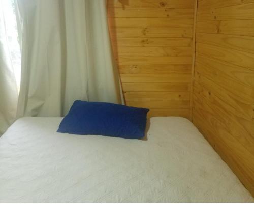 un letto con un cuscino blu sopra di Cabañas a Quemchi
