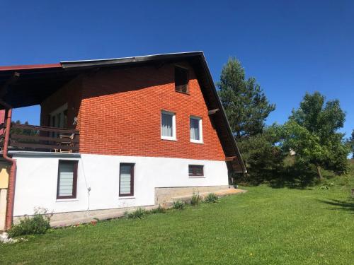 a house with a red roof on a green field at Mountain resort house - Planinska vikendica in Han Pijesak