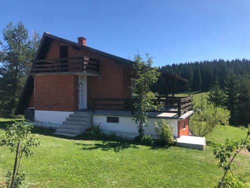 ein Haus auf einem Hügel mit einem Rasenplatz in der Unterkunft Mountain resort house - Planinska vikendica in Han Pijesak