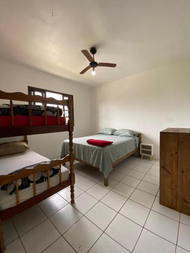 a bedroom with two bunk beds and a ceiling fan at Casa aconchegante in Garopaba