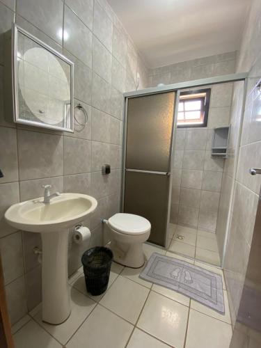 a bathroom with a toilet and a sink and a shower at Casa aconchegante in Garopaba