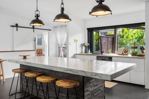 a kitchen with a large marble counter with stools at Summit to Sea, Elevated Luxury in Coolum Beach