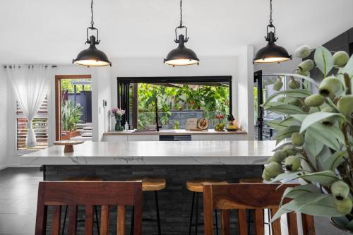 a kitchen with a large white counter and chairs at Summit to Sea, Elevated Luxury in Coolum Beach