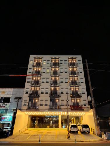 a large white building with windows and cars parked in front at Mango Suites - Angeles in Angeles
