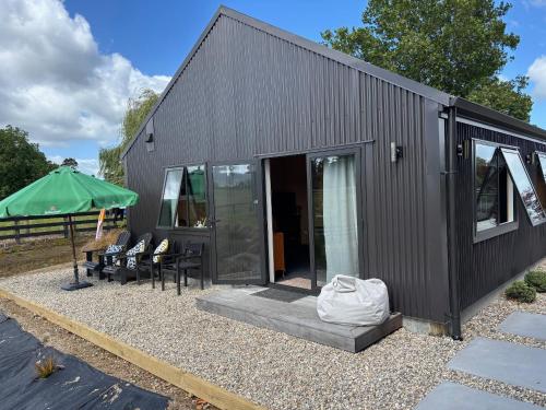 a black tiny house with a patio and a green umbrella at Cabin-on-Swayne in Cambridge