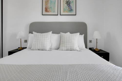 a white bed with white pillows and two lamps at Amazing 3 Bedrooms in Mayfair in London