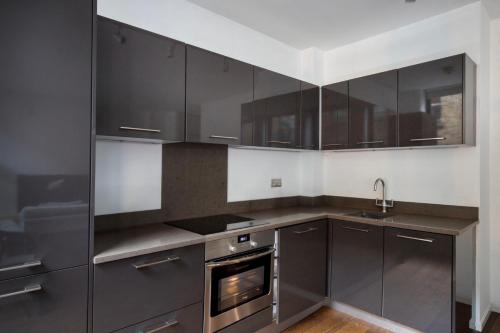 a kitchen with gray cabinets and a sink and an oven at Amazing 3 Bedrooms in Mayfair in London