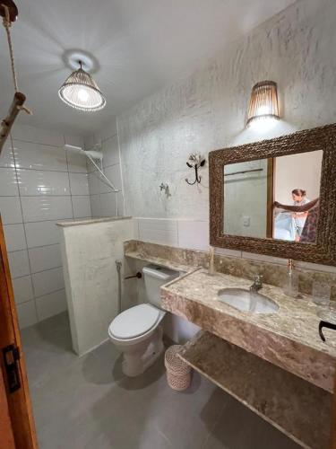 a bathroom with a sink and a toilet and a mirror at Pousada Villa Santorini Preá in Cruz