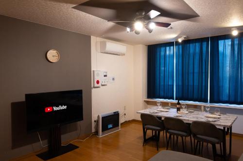 a dining room with a table with chairs and a tv at stay in tokiwa in Asahikawa