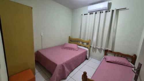 two beds in a small room with pink sheets at Terraço do Sol Apt 03 in Marcelino Ramos