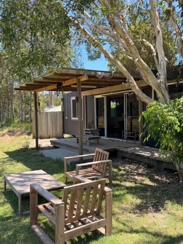 two chairs and a picnic table in front of a house at The Village Eco Stay Byron Bay in Byron Bay