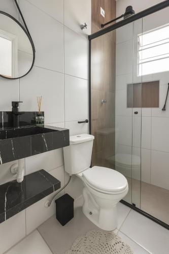 a bathroom with a toilet and a glass shower at Loft central perto da praia in Caraguatatuba