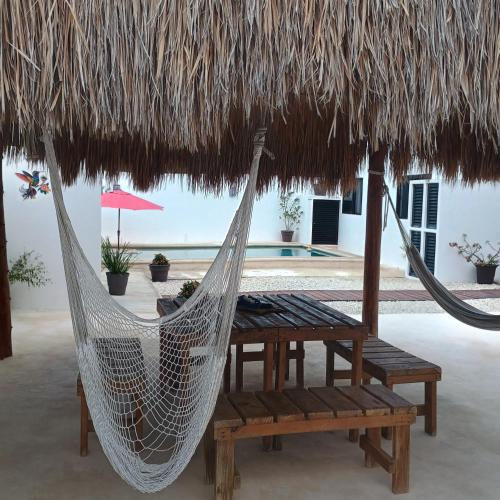 a hammock and bench under a straw umbrella at Casa Loto A in Chelem