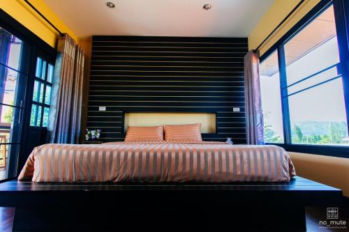 a bedroom with a large bed with a black headboard at Sethachan Poolvilla Khaoyai in Ban Rai Khlong Sai