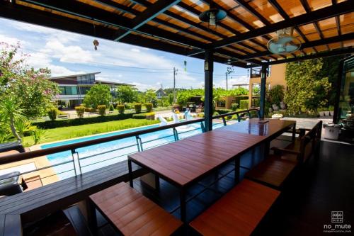 a patio with a wooden table and a swimming pool at Sethachan Poolvilla Khaoyai in Ban Rai Khlong Sai