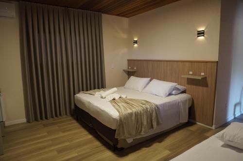 a bedroom with a large bed with white pillows at Hotel La Roza e Restaurante Grill in Penha