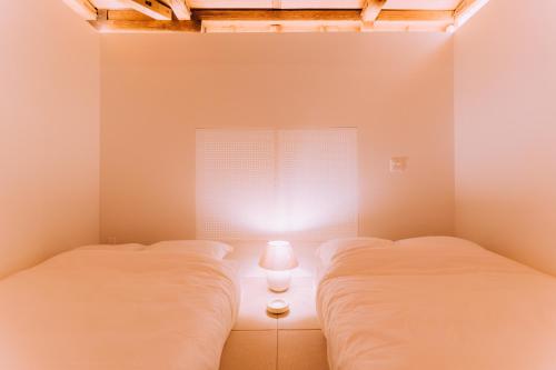 two beds in a room with a window at One Harajuku: Private Oasis in Tokyo