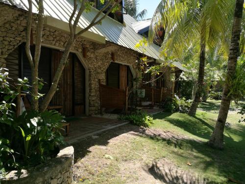 a stone house with a porch and palm trees at Ravenala Beach Bungalows in Moalboal