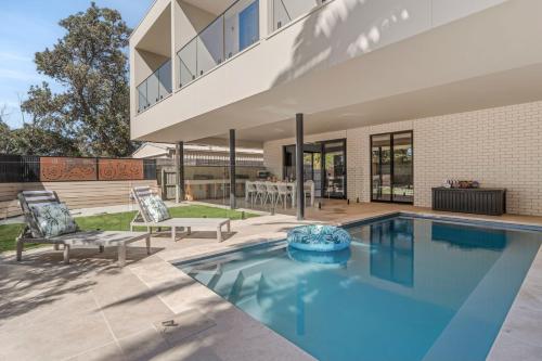 a house with a swimming pool with two chairs at Bonnyvale Dune Retreat I Ocean Grove in Ocean Grove