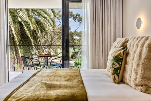 a bedroom with a bed and a balcony with a table at Bonnyvale Dune Retreat I Ocean Grove in Ocean Grove
