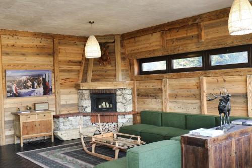 un soggiorno con divano verde e camino di Chalet Arpian Valmorel a Les Avanchers