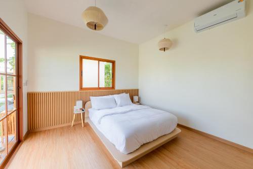 ein Schlafzimmer mit einem weißen Bett und einem Fenster in der Unterkunft Yugen House - Yuma in Nong Prue