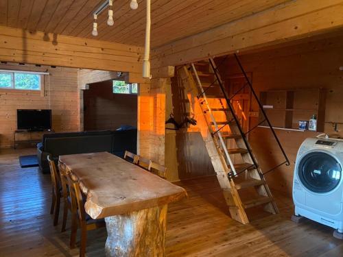 a living room with a wooden table and a ladder at large log cabin 桜 in Toyoura