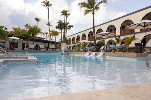 a swimming pool at a resort with palm trees at voco Surfside Aruba by IHG in Oranjestad
