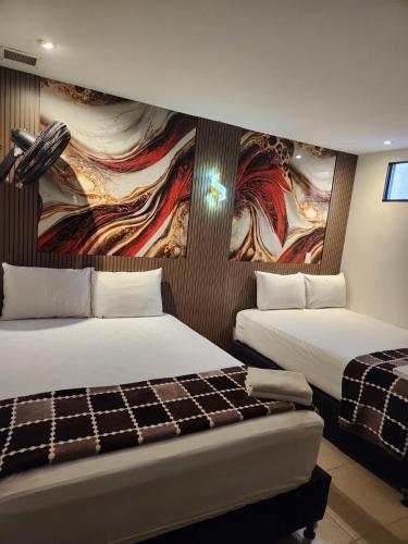 a hotel room with two beds and a painting on the wall at Hotel 50 Suites in Caldas