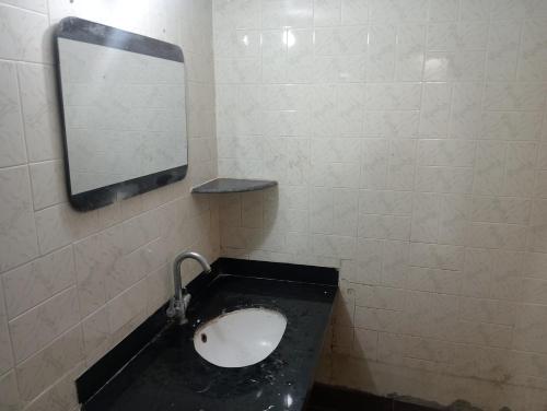 a bathroom with a sink and a mirror on a wall at SuryaVinayak Home Stay - 10min walk from Railway station in Ghātsīla