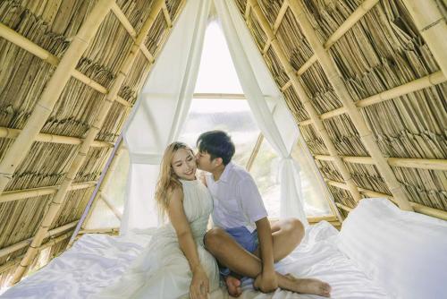 Ein Paar sitzt auf einem Bett vor einem Fenster in der Unterkunft LIA Retreat & Coffee 