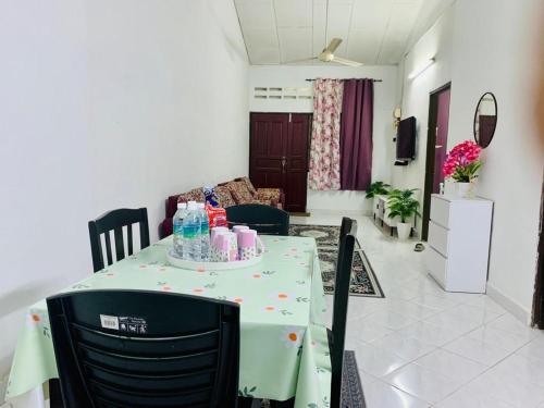 a table with a green table cloth on it in a living room at Homestay Hayyan in Kampong Terbak