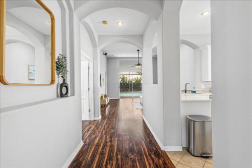 un corridoio di una casa con pareti bianche e pavimenti in legno di NEW - Poolside Oasis Heated POOL Home - 2000 SF a Zephyrhills