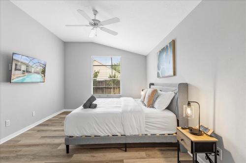 una camera da letto bianca con un letto e un ventilatore a soffitto di NEW - Poolside Oasis Heated POOL Home - 2000 SF a Zephyrhills