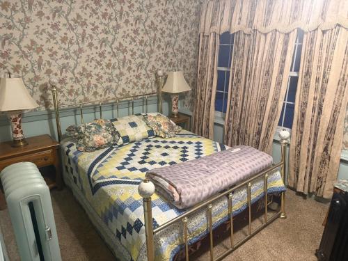ein Schlafzimmer mit einem Bett und zwei Lampen und einem Fenster in der Unterkunft Historic Rider's Inn in Mentor