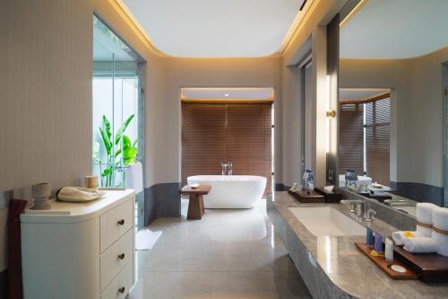 Un baño con una bañera grande y un lavabo grande. en Javana Royal Villas, en Seminyak
