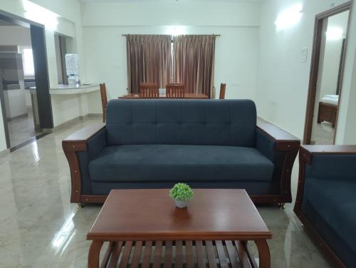 een woonkamer met een blauwe bank en een tafel bij Amaira Studio living - Coimbatore in Coimbatore
